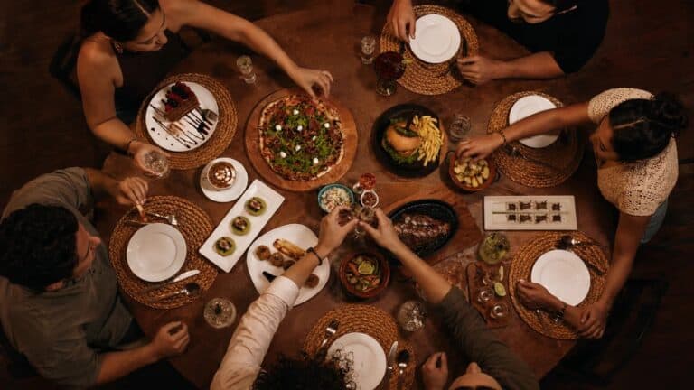 Grupo de viajeros compartiendo platillos mexicanos en una mesa de madera, vista desde arriba.