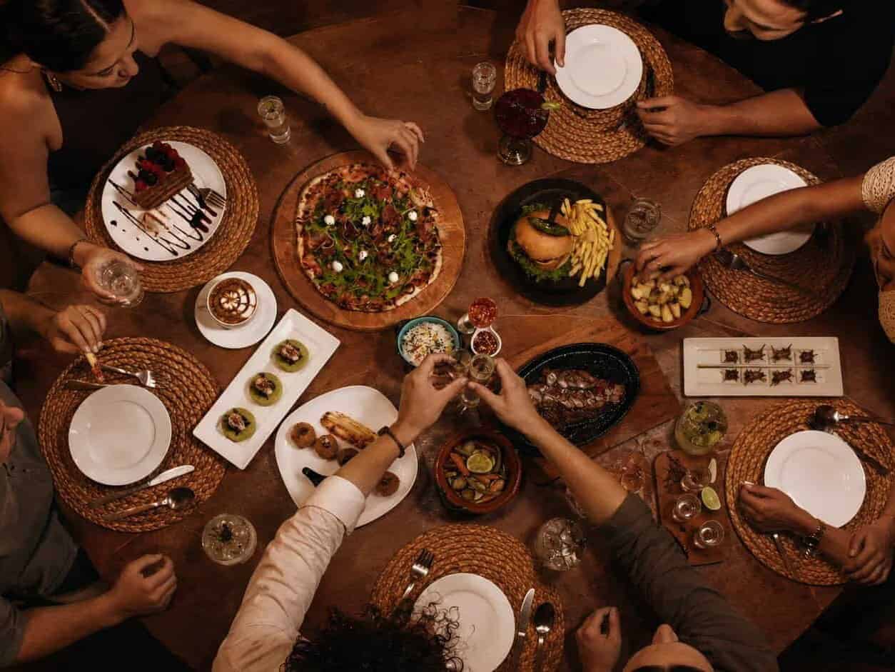 Grupo de viajeros compartiendo platillos mexicanos en una mesa de madera, vista desde arriba.