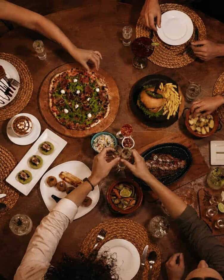 Group of travelers sharing Mexican dishes at a wooden table, seen from above.