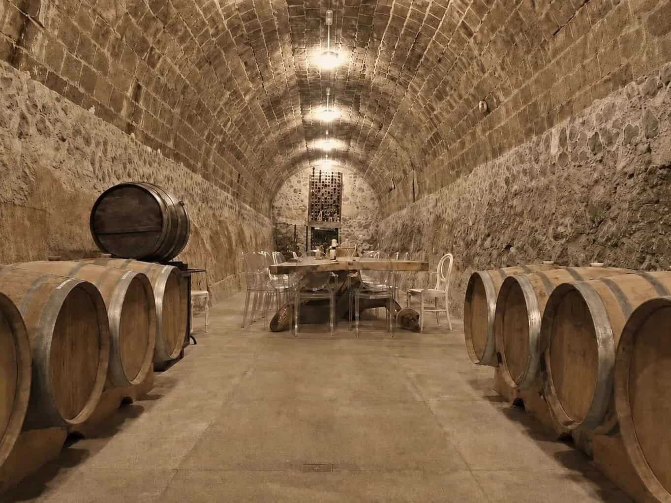 Cava con barricas de roble bajo una bóveda de piedra.
