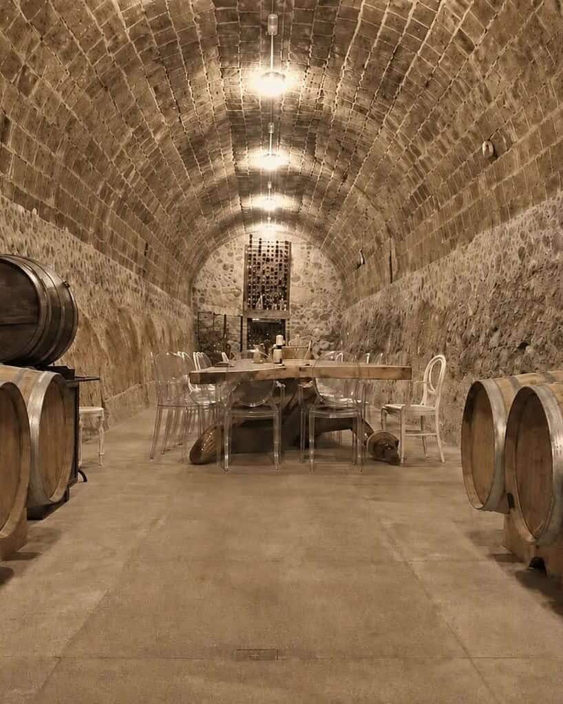 Cava con barricas de roble bajo una bóveda de piedra.