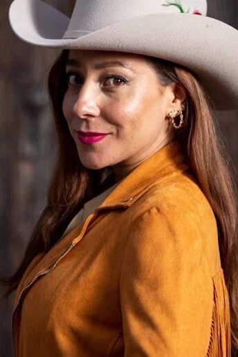 Woman with cowboy hat and camel leather jacket.