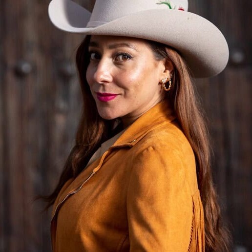 Woman with cowboy hat and camel leather jacket.