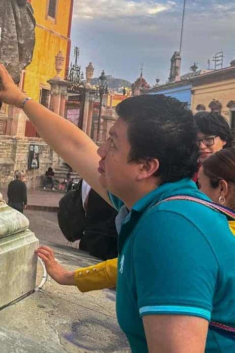 Participants of the inclusive cultural tour touch a sculpture in the historic center of Guanajuato.