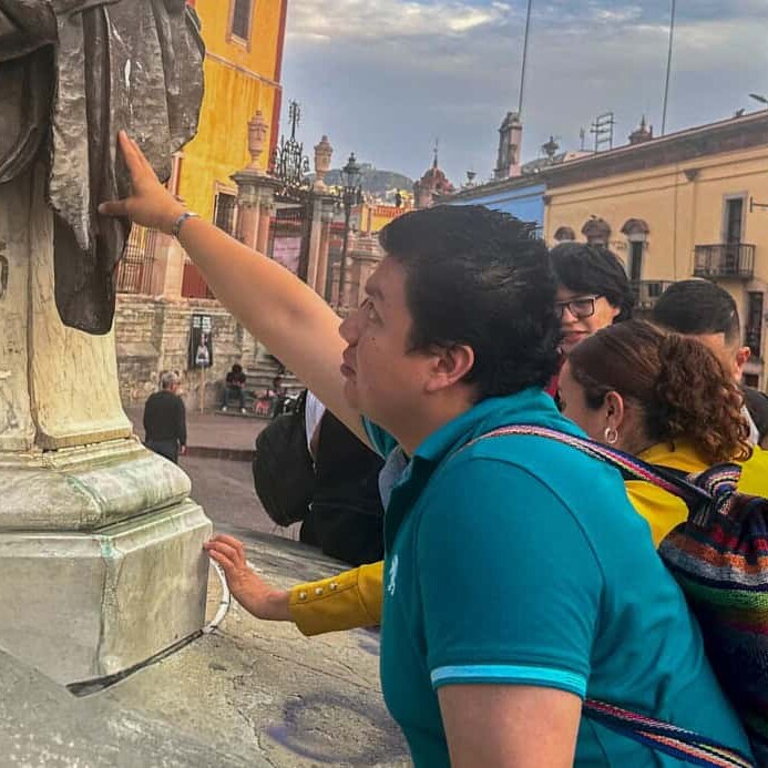 Participants of the inclusive cultural tour touch a sculpture in the historic center of Guanajuato.
