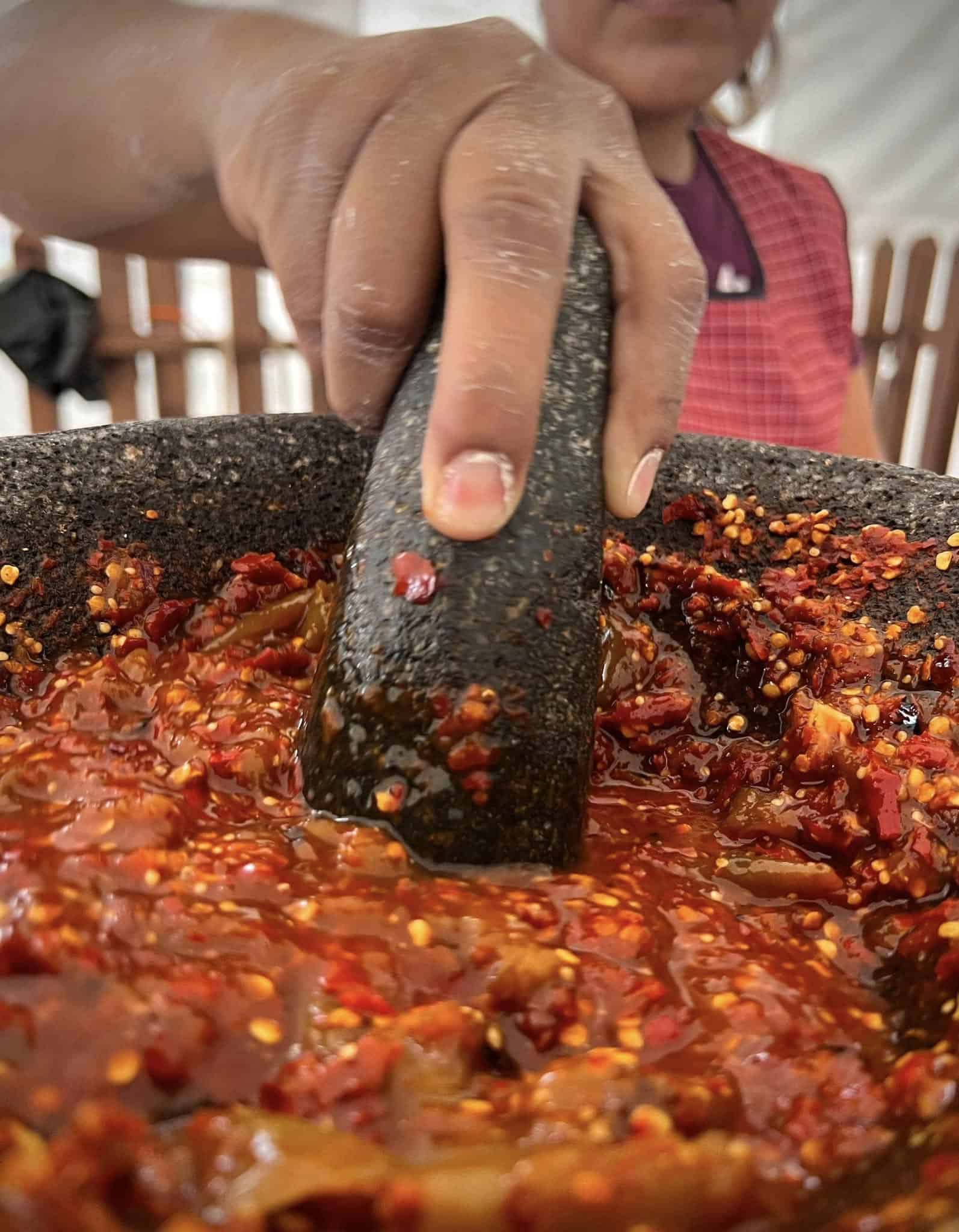 Persona machacando salsa en molcajete en Guanajuato, M&eacute;xico.