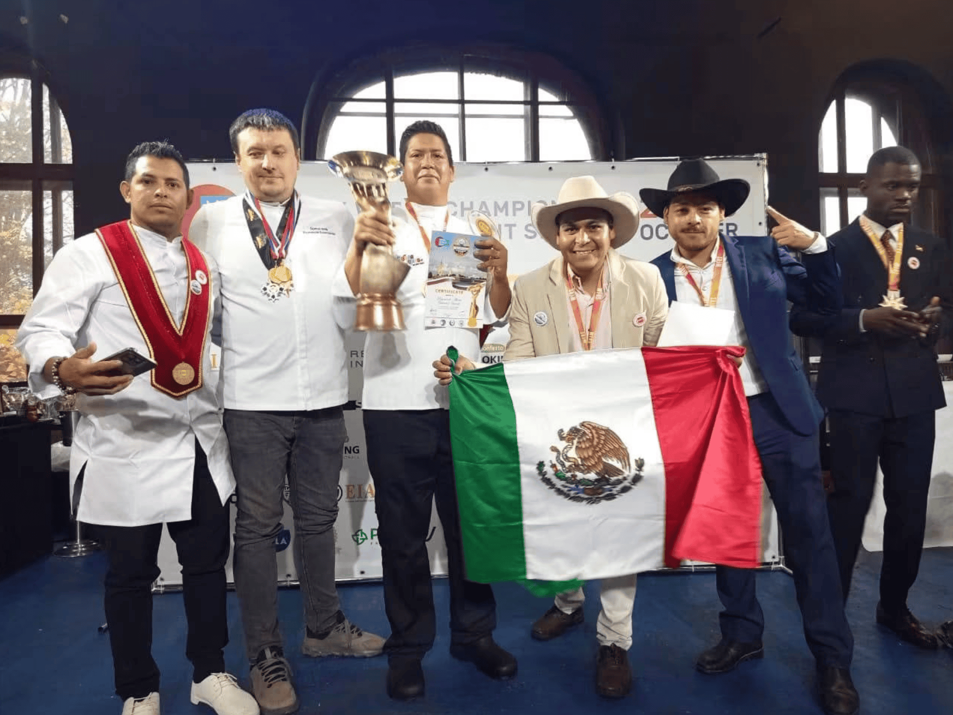 Equipo mexicano con trofeo y bandera de México en podium.