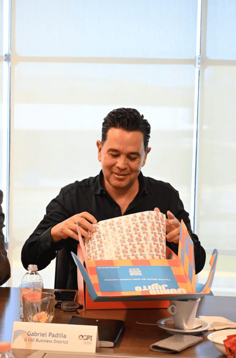 Hombre abriendo una caja con productos promocionales en una oficina moderna.