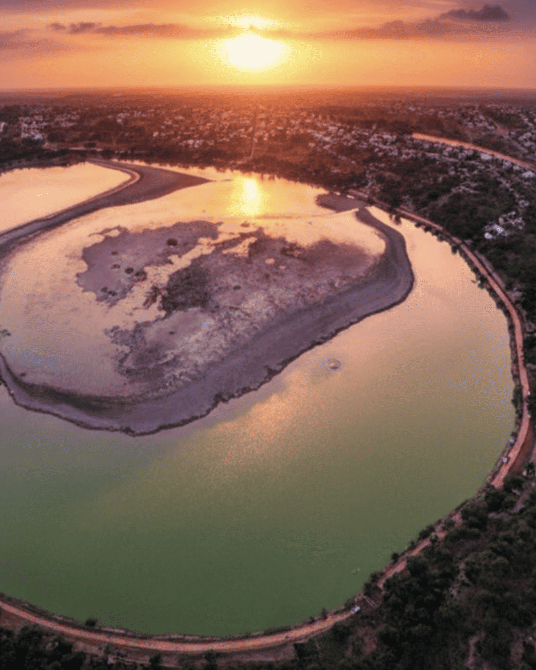 Hermosa vista aérea del río en Guanajuato al atardecer, reflejando el cielo naranja y rosado.