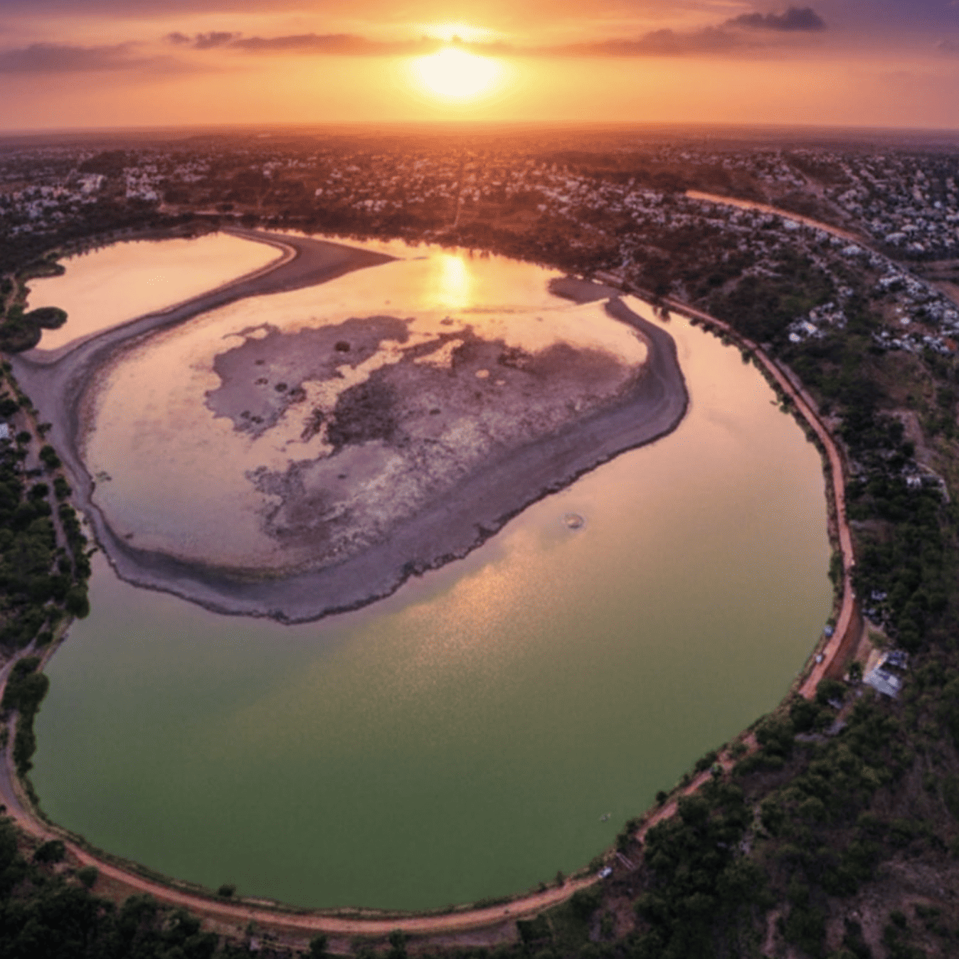 Hermosa vista aérea del río en Guanajuato al atardecer, reflejando el cielo naranja y rosado.