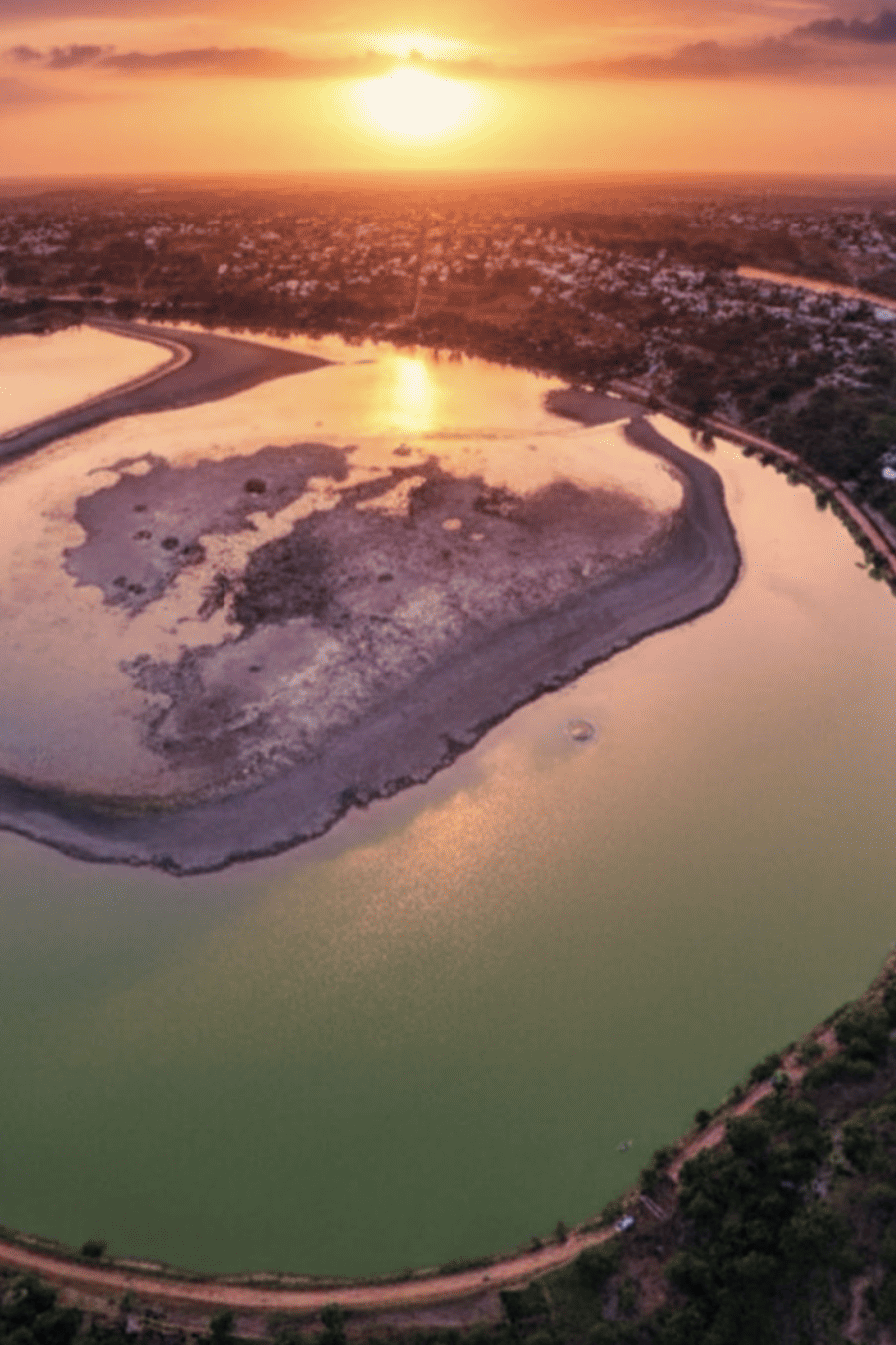 Hermosa vista aérea del río en Guanajuato al atardecer, reflejando el cielo naranja y rosado.