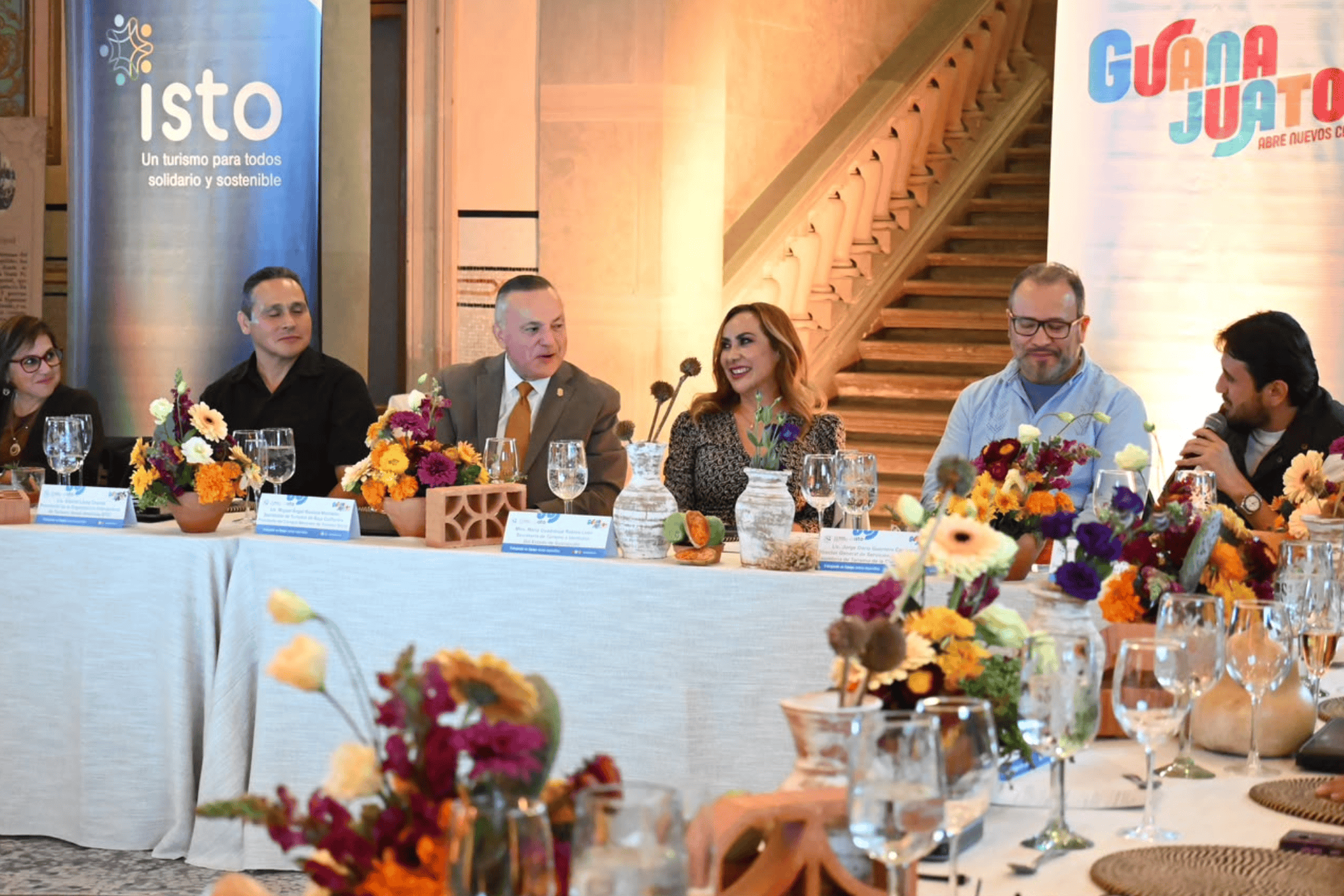 Mesa de discusión en evento de turismo social en Guanajuato con flores y panelistas.